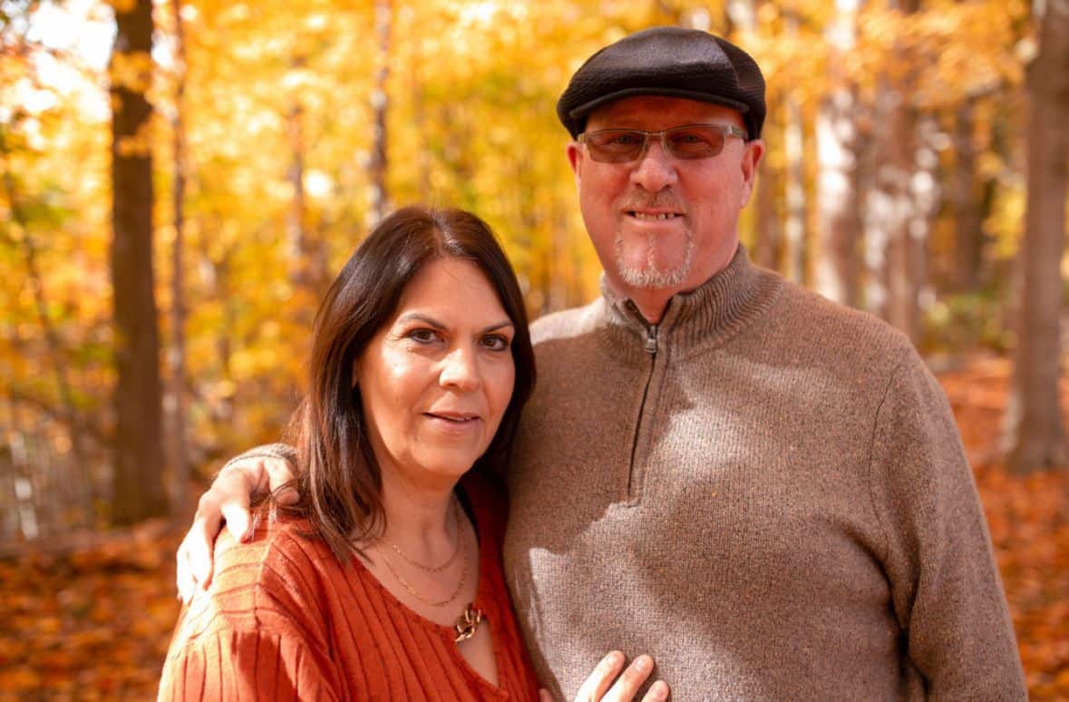 Smiling couple standing among autumn trees